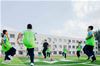 Students warm up for a football match on a rubber field made using recycled Nike shoes